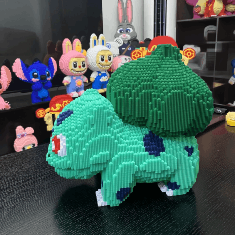 Pokemon Bulbasaur & Charmander Building Blocks – DIY Model Toy A 3D brick-built model of Bulbasaur from Pokémon, constructed from interlocking plastic bricks, displayed on a dark reflective surface with other toy figures in the background.