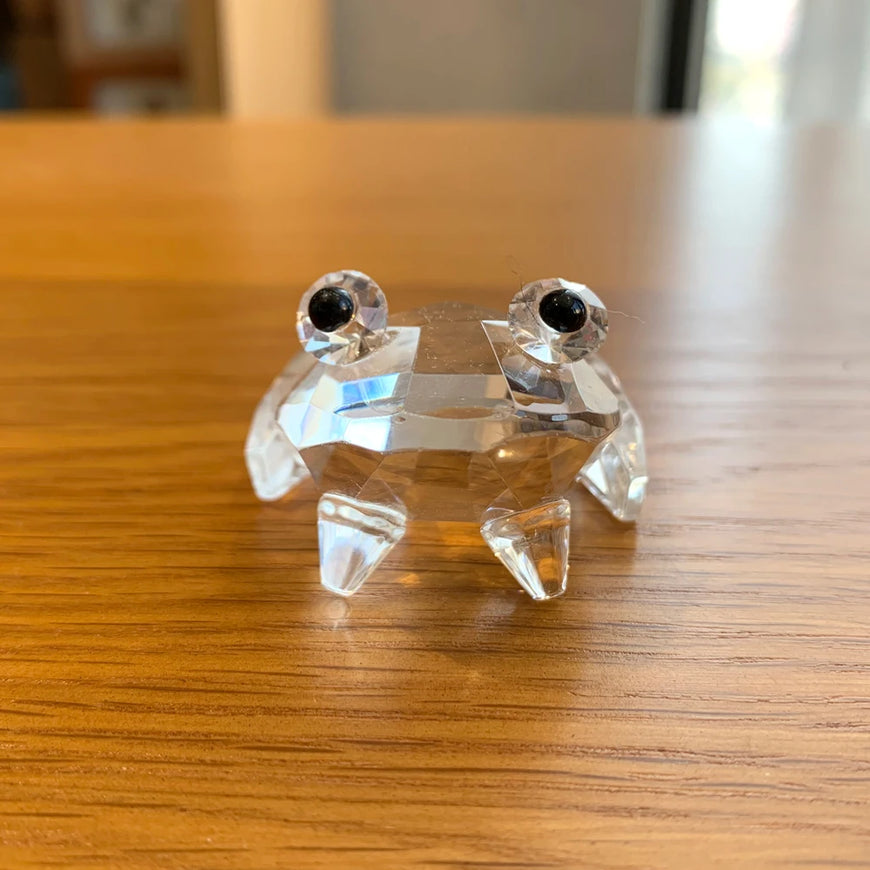 Clear crystal frog figurine on a wooden surface