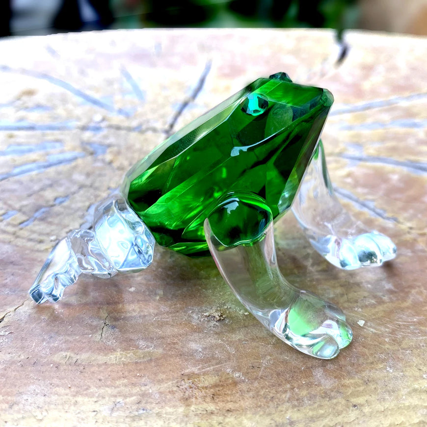 Green glass frog on a wooden surface