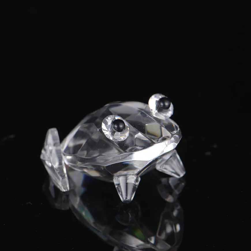 Crystal frog figurine on a reflective black surface