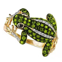 Frog-shaped ring with green gemstones and gold accents on a white background