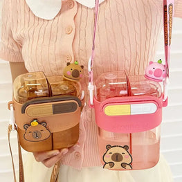 Two cute water bottles with bear-themed covers, shown being held by a person wearing a pink cardigan. One bottle is brown with a brown bear cover, and the other is pink with a pink bear cover.