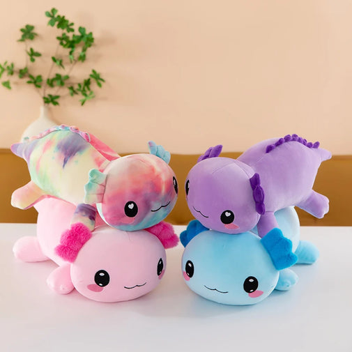 Four colorful plush toys resembling sea creatures on a light surface with a plant in the background.