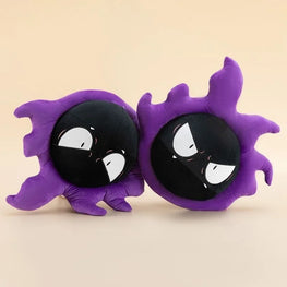 Two purple ghost-shaped plush pillows with black circular faces and white eyes, shown side by side on a plain beige background.