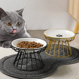 Cat looking at a raised pet bowl with food on a textured mat.