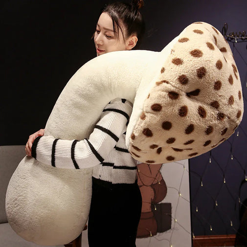 Person holding a large, soft, U-shaped pillow with a polka dot pattern.
