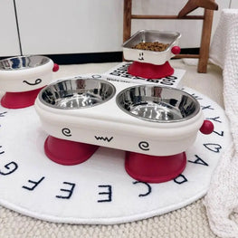 Pet feeding station with two bowls on a circular mat with lettering