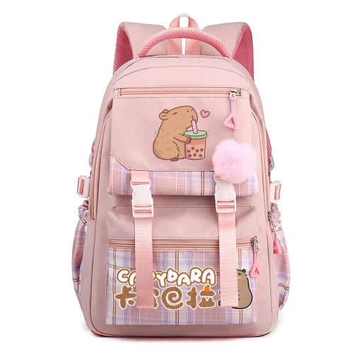 A pink school backpack with cute cartoon graphics, including a capybara holding a bubble tea cup and the text 'Capydara 卡巴拉' on a plaid pocket. It features a fluffy pink pom-pom charm and adjustable straps, shown against a plain white background.