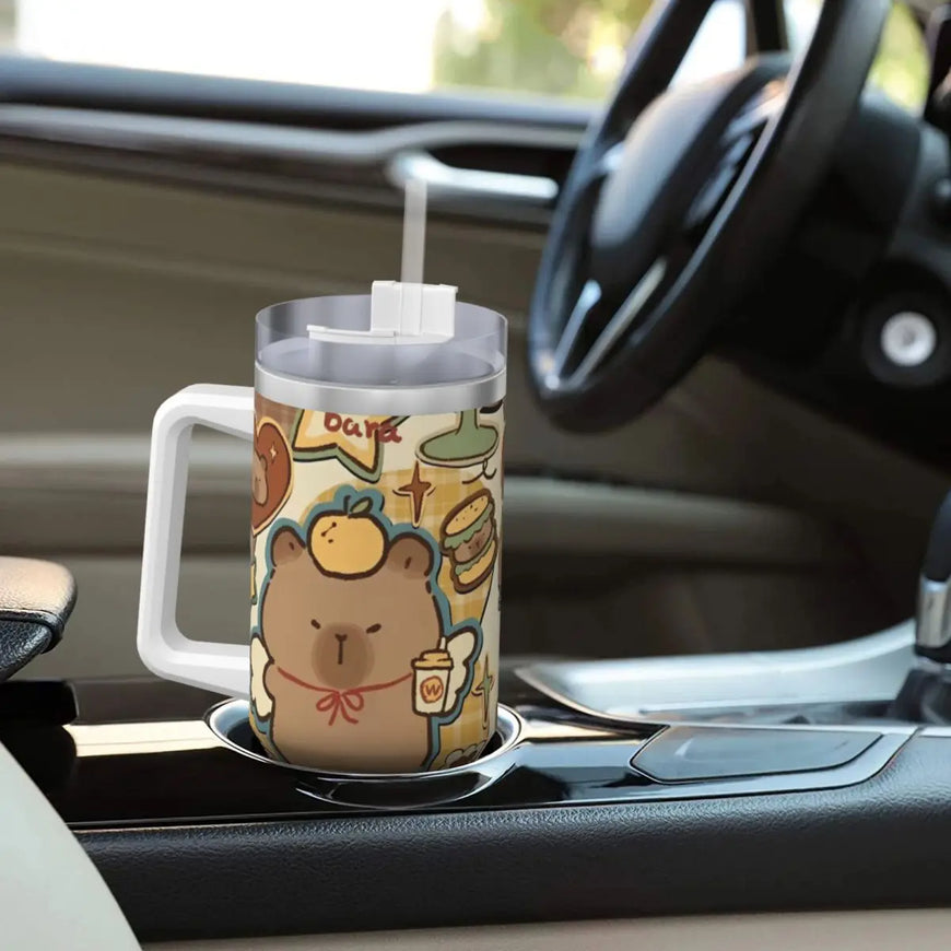 A handled stainless steel travel tumbler with a cartoon capybara and coffee-themed illustration, shown in a car cup holder.