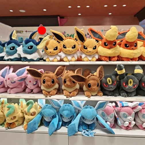 Three shelves filled with colorful plush toy Pokémon, including Eevee, Eevee variants, and other shiny-colored plushies, displayed in a store setting.