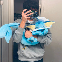 Person holding a large blue plush toy in front of a mirror