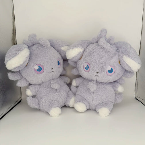 Two gray plush toys with white accents on a white surface.