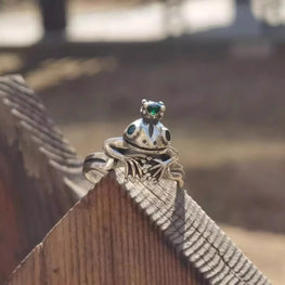 Silver ring with green gemstone on a wooden surface