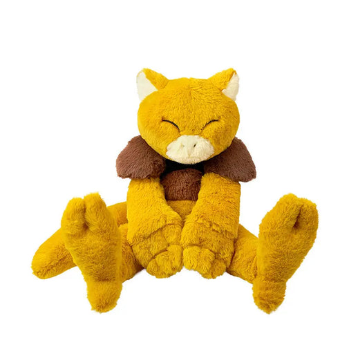 A plush toy shaped like a sleeping fox or cat in a seated position, made of soft yellow fabric with brown shoulder accents, a cream muzzle, and white inner ears, photographed on a plain white background.
