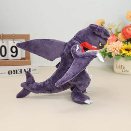 Plush toy shark with a red mouth on a light surface with decorative items in the background