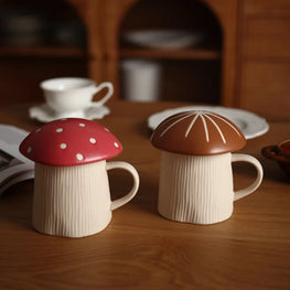 Two ceramic mushroom-shaped mugs on a wooden surface with a blurred background.