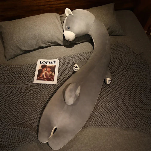 Gray plush toy resembling a snake on a bed with a Loewe magazine.