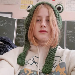Person wearing a green frog hood in front of a chalkboard
