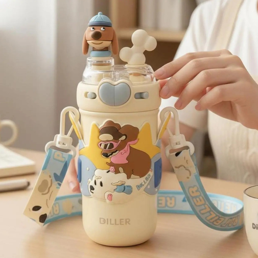 A cute cream-colored water bottle with cartoon dog graphics, a blue strap, and a small dog figure on top, shown on a table with a person's hand adjusting the lid.