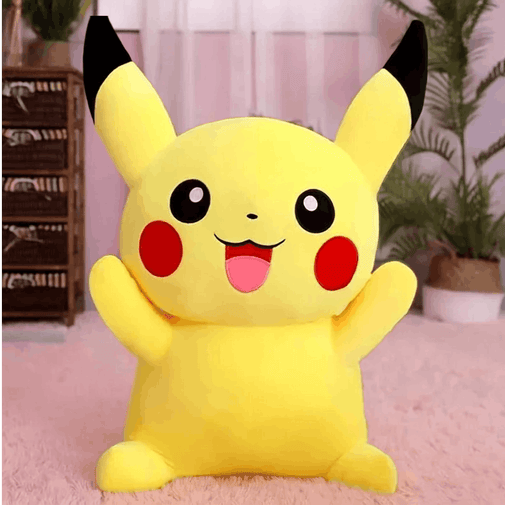 A large yellow Pikachu plush toy with black-tipped ears, red cheeks, and a smiling face, posed on a pink rug in a softly decorated room with plants and furniture in the background.