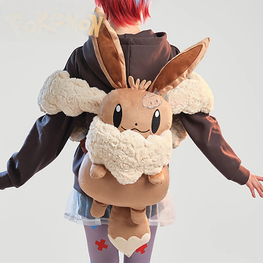A person wearing a brown hoodie and skirt holds up a large plush Eevee backpack against their back. The backpack features a tan body with fluffy cream fleece accents on the ears and neck area.